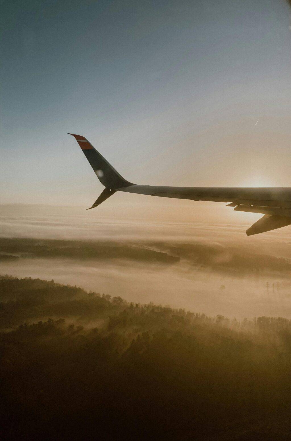 A breathtaking view of an airplane wing over a fog-covered autumn landscape at sunrise in Germany.