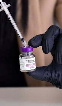 Close-up of a syringe and Botox vial handled by medical professional.