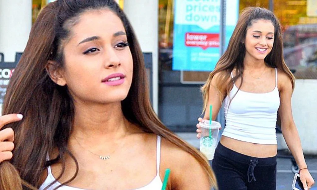 Ariana Grande shows off svelte figure in midriff revealing tank top.